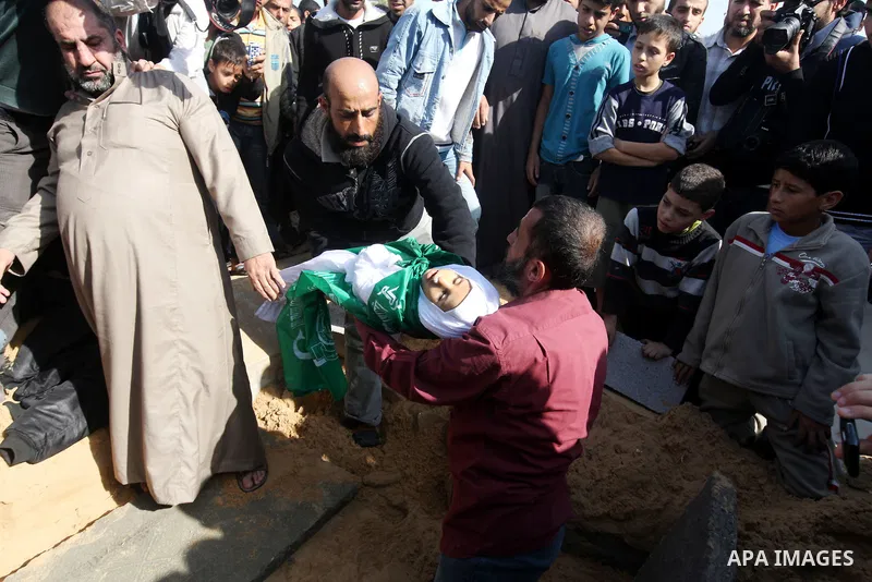 A Palestinian man carries the body of one of children to the grave during their funeral in the northern Gaza Strip November 18, 2012. Two children Jumana Abu Seifan, 18 months old, and her brother Tamer, three and a half...