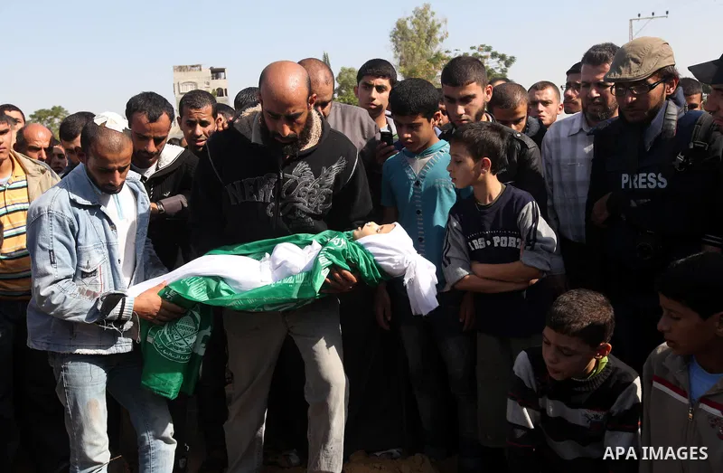 A Palestinian man carries the body of one of children to the grave during their funeral in the northern Gaza Strip November 18, 2012. Two children Jumana Abu Seifan, 18 months old, and her brother Tamer, three and a half...