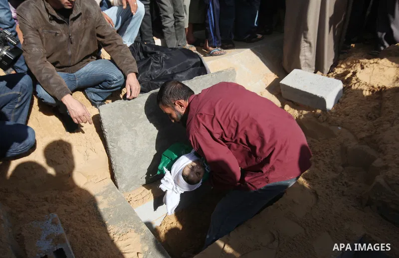 A Palestinian man carries the body of one of children to the grave during their funeral in the northern Gaza Strip November 18, 2012. Two children Jumana Abu Seifan, 18 months old, and her brother Tamer, three and a half...