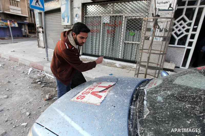A Palestinian journalist inspects his work car in Gaza City on November 18, 2012. An Israeli air strike hit a Gaza City media building on November 18, injuring at least six journalists, as a separate raid in northern Gaz...