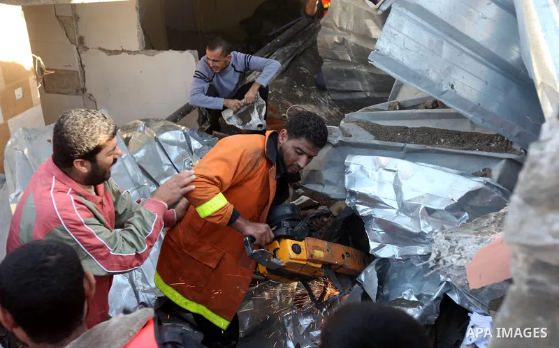 Palestinian civil defense staff use equipment to cut through metal as they search for victims stuck under the rubble of a destroyed house after it was damaged during an Israeli air strike on Gaza City on November 18, 201...