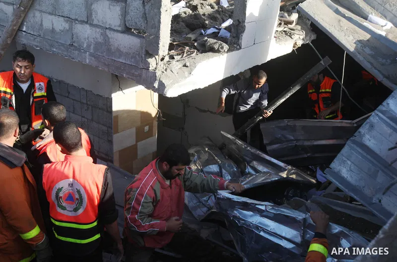 Palestinian civil defense staff use equipment to cut through metal as they search for victims stuck under the rubble of a destroyed house after it was damaged during an Israeli air strike on Gaza City on November 18, 201...
