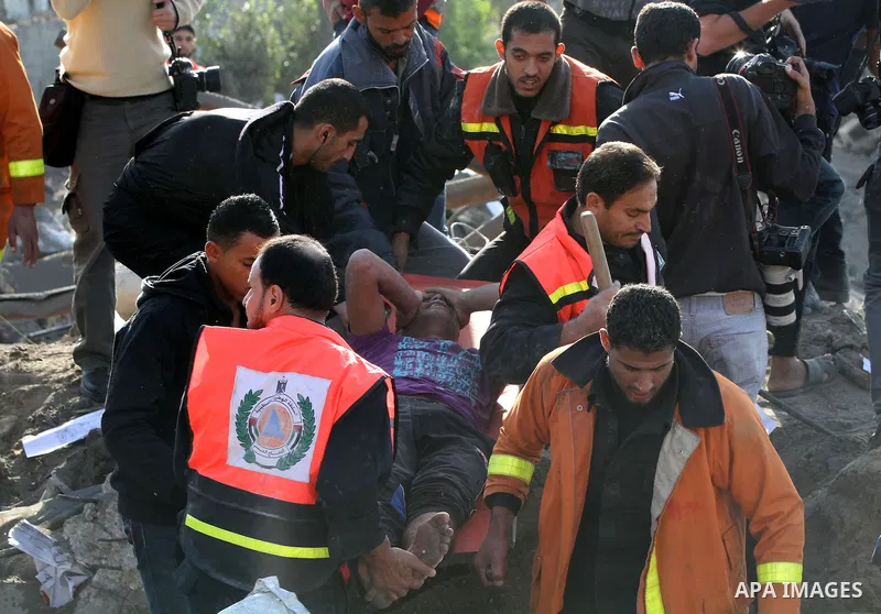 Palestinian civil defence staff carry a survivor on a stretcher after he was pulled out from under the rubble of a destroyed house following an Israeli air strike on Gaza City on November 18, 2012. Fresh Israeli air stri...