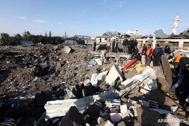 Palestinians inspect the damage on a rubble of a destroyed house after it was damaged during an Israeli air strike on Gaza City on November 18, 2012. Fresh Israeli air strikes hit a Gaza City media centre and homes in no...