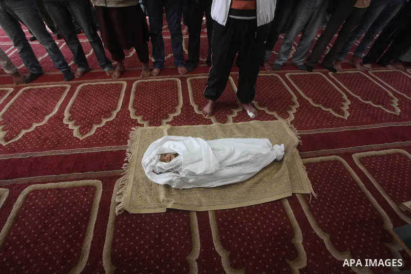 Palestinians pray over the body of one and a half year-old baby, Iyad Abu Khoussa, during his funeral at a mosque in Bureij Refugee Camp, central Gaza Strip, Sunday, Nov. 18, 2012. The baby boy was one of five Palestinia...
