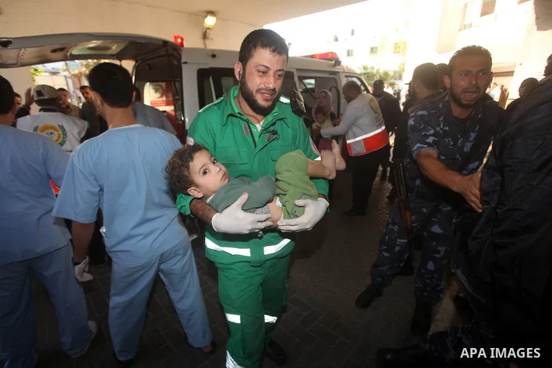 A Palestinian medic carries a wounded baby on a stretcher to Al-Shifa hospital in Gaza City on November 18, 2012. An Israeli air strike hit a Gaza City media building on November 18, injuring at least six journalists, as...