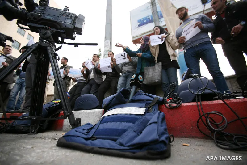 Palestinian Journalists hold placards during a protest against the Israeli military attacks on the palestinian Gaza strip, in the West Bank town of Hebron, on November 18, 2012. An Israeli air strike hit a Gaza City medi...