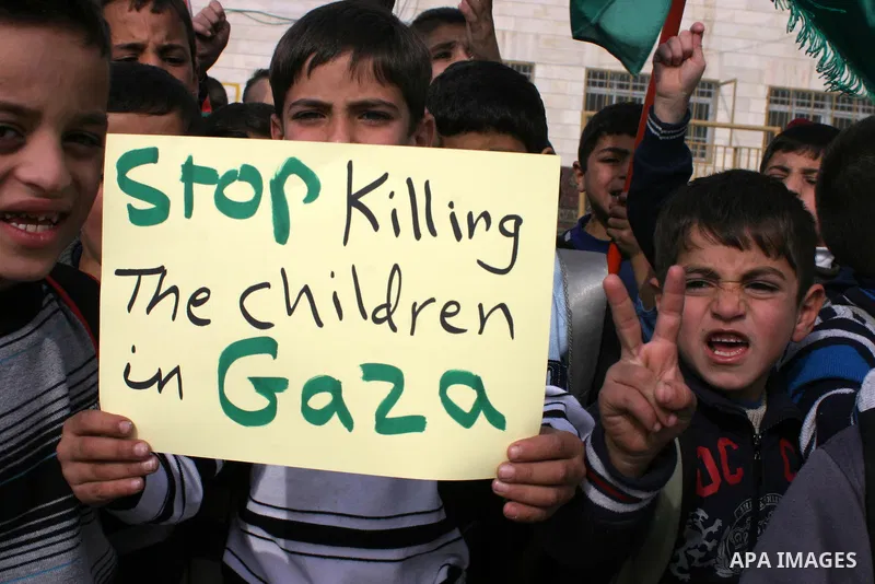 Palestinian children shout slogans and hold placards during a protest in solidarity with the children of Gaza, in the West Bank city of Hebron, on November 18, 2012. Israeli aircraft killed five Palestinian children in o...