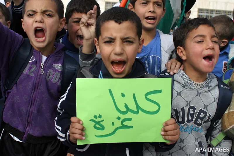 Palestinian children shout slogans and hold placards during a protest in solidarity with the children of Gaza, in the West Bank city of Hebron, on November 18, 2012. Israeli aircraft killed five Palestinian children in o...