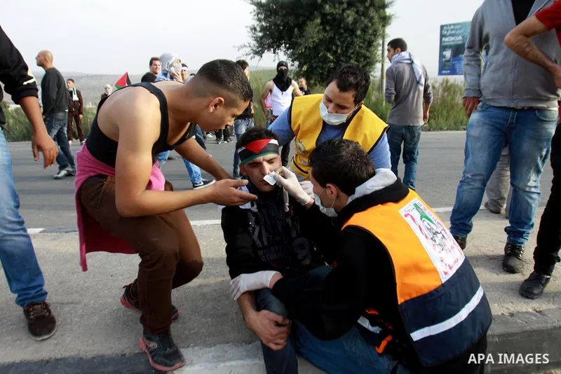 Palestinian medics treat a wounded protester during clashes following a protest against Israel's operations in the Gaza Strip, at Howwara checkpoint near Nablus, the West Bank, 18 November 2012. Reports state that the Is...