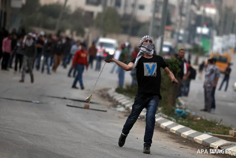 A Palestinian protester throws stones at Israeli border policemen during clashes outside Ofer prison near the West Bank city of Ramallah November 18, 2012. The clashes broke out following a protest against Israel's milit...