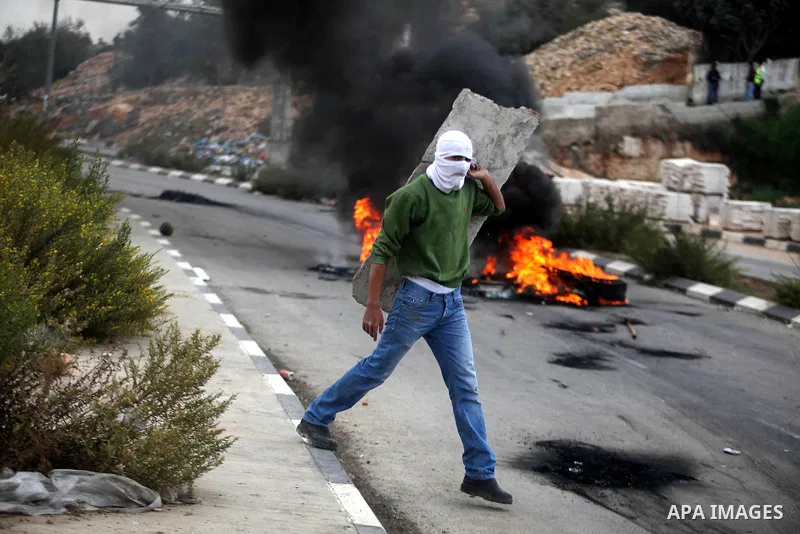 A Palestinian protester throws stones at Israeli border policemen during clashes outside Ofer prison near the West Bank city of Ramallah November 18, 2012. The clashes broke out following a protest against Israel's milit...