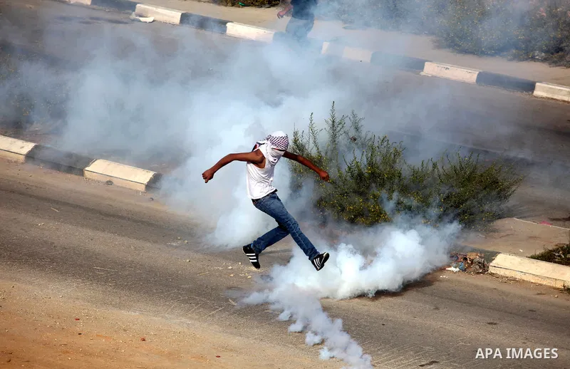 A Palestinian protester runs cover from tear gas fired by Israeli border policemen during clashes outside Ofer prison near the West Bank city of Ramallah November 18, 2012. The clashes broke out following a protest again...