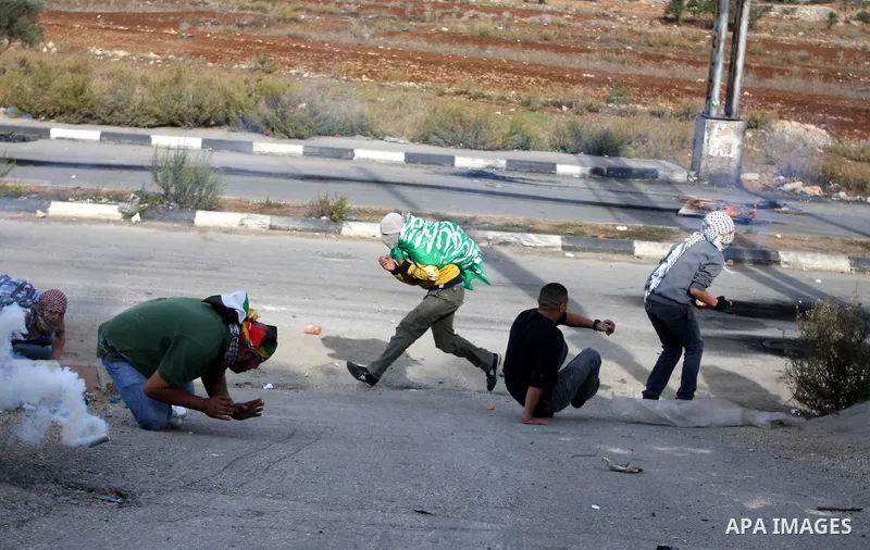 Palestinian protesters take cover from tear gas fired by Israeli border policemen during clashes outside Ofer prison near the West Bank city of Ramallah November 18, 2012. The clashes broke out following a protest agains...