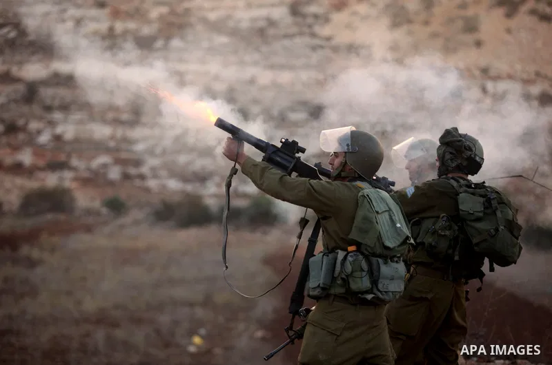An Israeli border policeman shoots a tear gas canister at Palestinian protesters during clashes outside Ofer prison near the West Bank city of Ramallah November 18, 2012. The clashes broke out following a protest against...