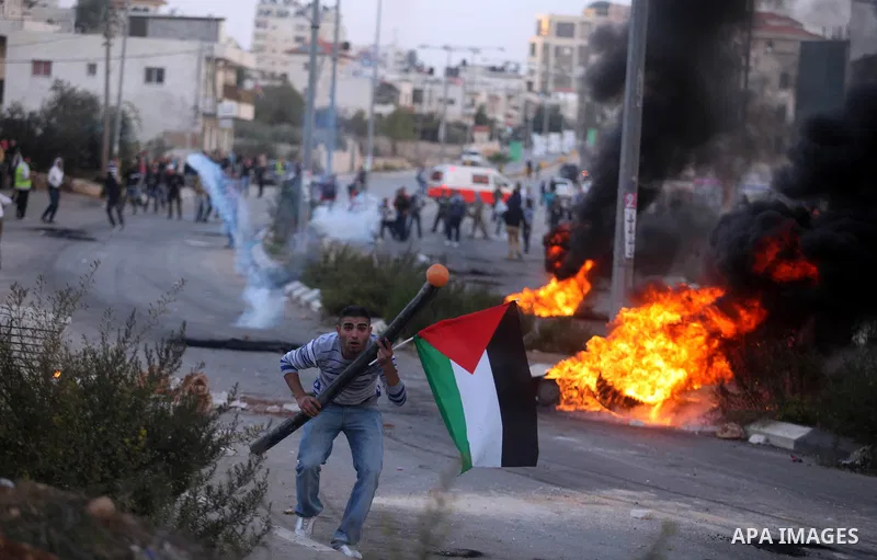 A Palestinian protester throws stones at Israeli border policemen during clashes outside Ofer prison near the West Bank city of Ramallah November 18, 2012. The clashes broke out following a protest against Israel's milit...