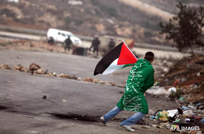 A Palestinian protester runs cover from tear gas fired by Israeli soldiers during clashes outside Ofer prison near the West Bank city of Ramallah November 18, 2012. The clashes broke out following a protest against Israe...