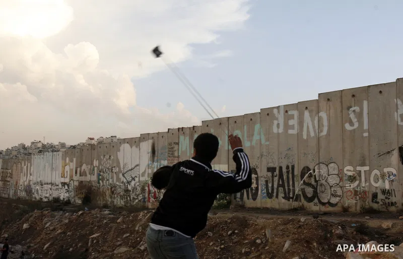 A Palestinian protester throws stones at Israeli border policemen during a Palestinian protest at Damascus Gate in East Jerusalem, 18 November 2012, showing solidarity with the Palestinians in the Gaza Strip, as hostilit...