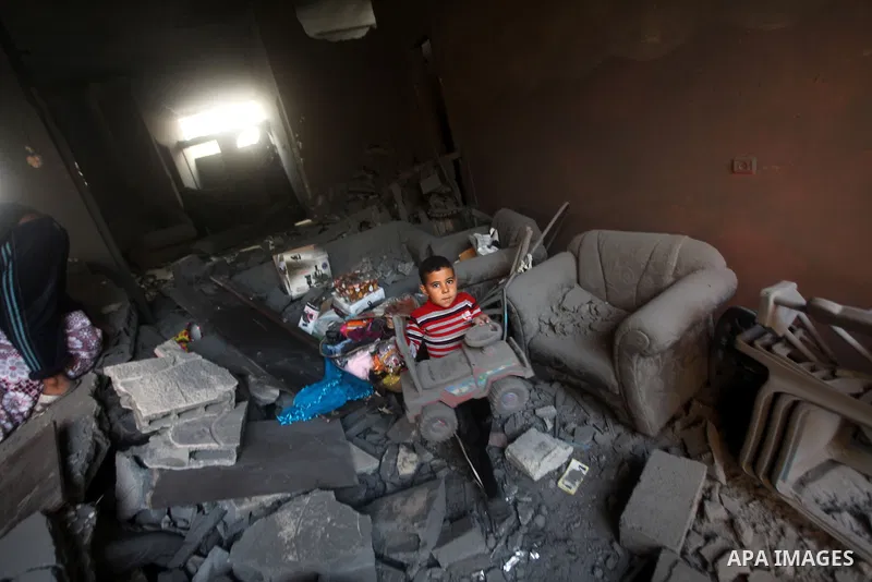 A Palestinian boy carries his bicycle toy as he searches the debris of a destroyed home following an Israeli air strike in Gaza City, on November 19, 2012. Israeli air strikes on Sunday killed 31 Palestinians in the bloo...