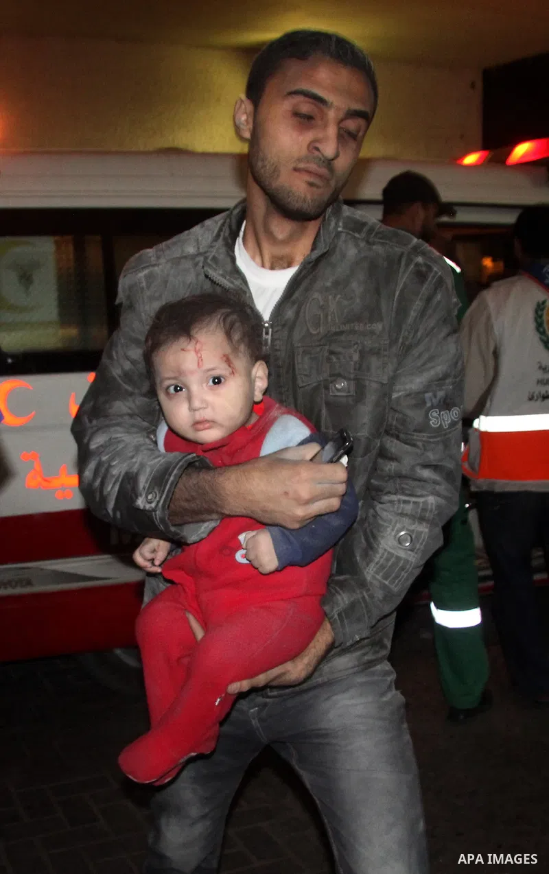 A Palestinian man carries a wounded baby boy at al-Shifa hospital after an Israeli air strike in Gaza city, on November 19, 2012. Israeli air strikes on Sunday killed 31 Palestinians in the bloodiest day so far of its ai...