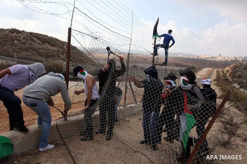 Palestinian youths cut a section of Israel's separation fence in the West Bank village of Ramat near Ramallah to protest against Israel's military action on the Gaza Strip, on November 19, 2012 . Israeli air strikes acro...