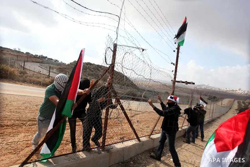 Palestinian youths cut a section of Israel's separation fence in the West Bank village of Ramat near Ramallah to protest against Israel's military action on the Gaza Strip, on November 19, 2012 . Israeli air strikes acro...