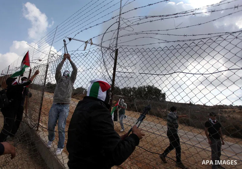 Palestinian youths cut a section of Israel's separation fence in the West Bank village of Ramat near Ramallah to protest against Israel's military action on the Gaza Strip, on November 19, 2012 . Israeli air strikes acro...