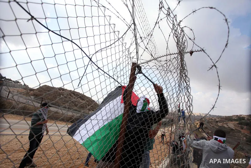 Palestinian youths cut a section of Israel's separation fence in the West Bank village of Ramat near Ramallah to protest against Israel's military action on the Gaza Strip, on November 19, 2012 . Israeli air strikes acro...