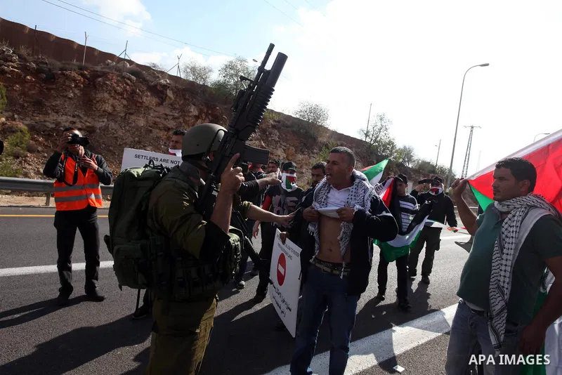Israeli soldiers stand guard as Palestinian and foreign activists block the road between Ramallah and Nablus to protest against Israel's military action on the Gaza Strip, on November 19, 2012 in the West Bank village of...