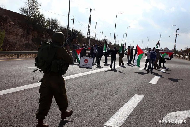 Israeli soldiers stand guard as Palestinian and foreign activists block the road between Ramallah and Nablus to protest against Israel's military action on the Gaza Strip, on November 19, 2012 in the West Bank village of...