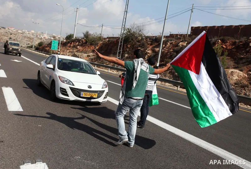 Palestinian and foreign activists block the road between Ramallah and Nablus to protest against Israel's military action on the Gaza Strip, on November 19, 2012 in the West Bank village of Silwad . Israeli air strikes ac...