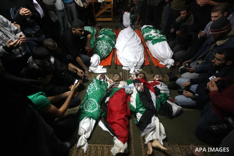 Palestinian mourners gather around the bodies of the al-Dallu family during their funeral in Gaza City, 19 November 2012. Nine members of the al-Dallu family died when Israeli forced hit their building in Gaza City one d...