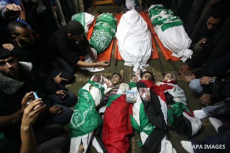 Palestinian mourners gather around the bodies of the al-Dallu family during their funeral in Gaza City, 19 November 2012. Nine members of the al-Dallu family died when Israeli forced hit their building in Gaza City one d...