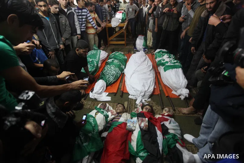 Palestinian mourners gather around the bodies of the al-Dallu family during their funeral in Gaza City, 19 November 2012. Nine members of the al-Dallu family died when Israeli forced hit their building in Gaza City one d...