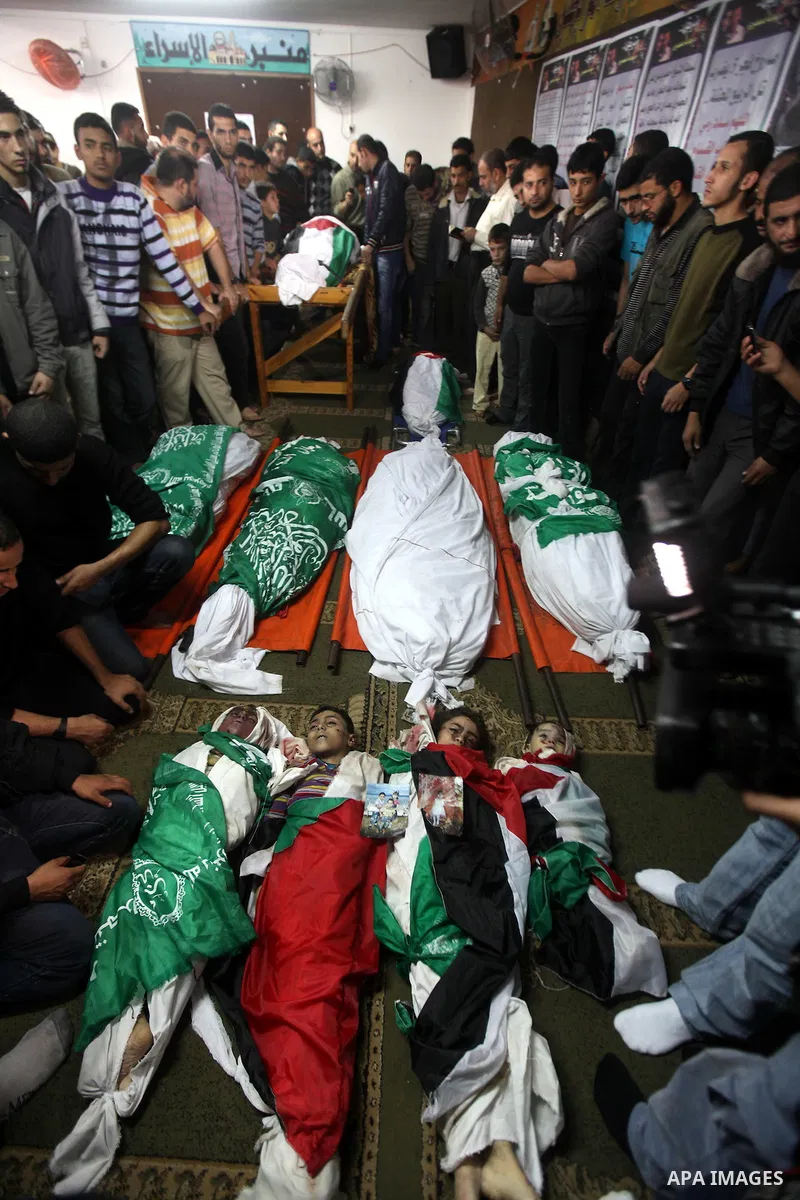 Palestinian mourners gather around the bodies of the al-Dallu family during their funeral in Gaza City, 19 November 2012. Nine members of the al-Dallu family died when Israeli forced hit their building in Gaza City one d...