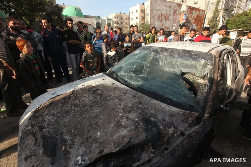 Palestinians gather around a destroyed car which targeted by Israeli airstrike in the northen Gaza city, 19 November, 2012. Israeli aircraft killed A Palestinian and wounded two others in the raid. Media reports that Isr...
