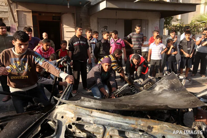 Palestinians gather around a destroyed car which targeted by Israeli airstrike in the northen Gaza city, 19 November, 2012. Israeli aircraft killed A Palestinian and wounded two others in the raid. Media reports that Isr...
