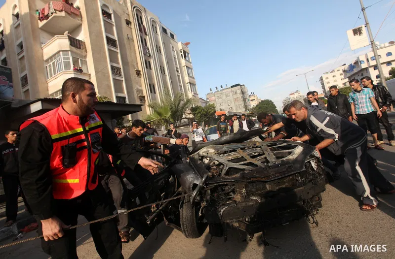 Palestinians gather around a destroyed car which targeted by Israeli airstrike in the northen Gaza city, 19 November, 2012. Israeli aircraft killed A Palestinian and wounded two others in the raid. Media reports that Isr...