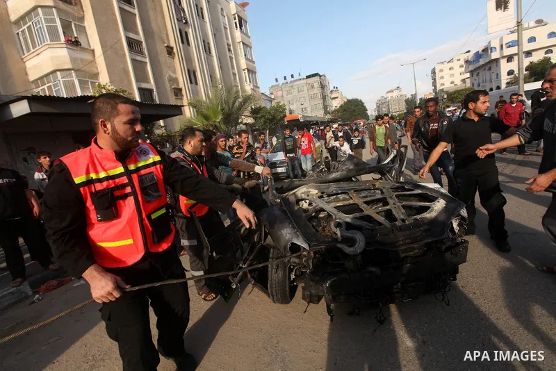 Palestinians gather around a destroyed car which targeted by Israeli airstrike in the northen Gaza city, 19 November, 2012. Israeli aircraft killed A Palestinian and wounded two others in the raid. Media reports that Isr...