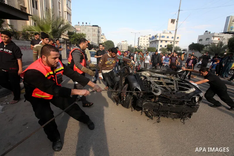 Palestinians gather around a destroyed car which targeted by Israeli airstrike in the northen Gaza city, 19 November, 2012. Israeli aircraft killed A Palestinian and wounded two others in the raid. Media reports that Isr...