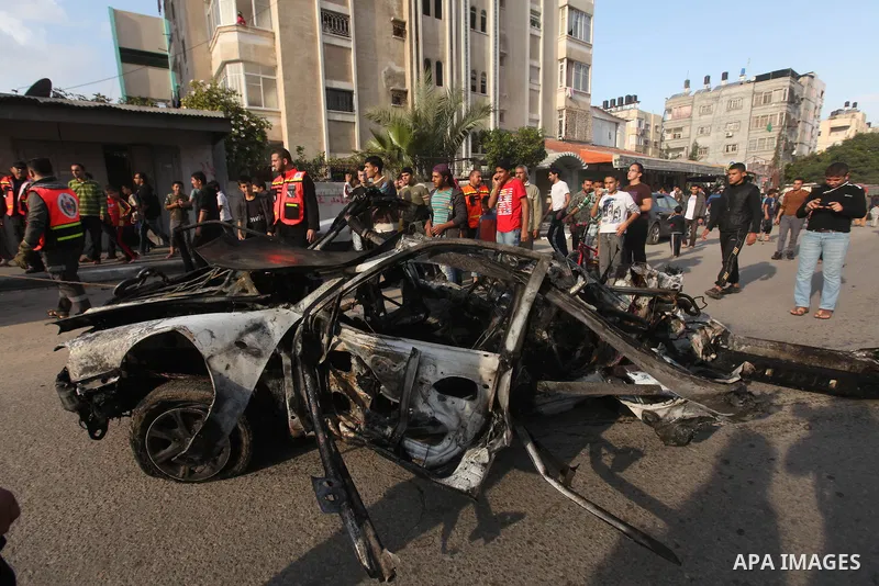 Palestinians gather around a destroyed car which targeted by Israeli airstrike in the northen Gaza city, 19 November, 2012. Israeli aircraft killed A Palestinian and wounded two others in the raid. Media reports that Isr...