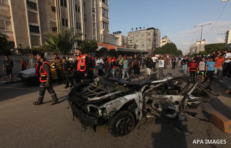Palestinians gather around a destroyed car which targeted by Israeli airstrike in the northen Gaza city, 19 November, 2012. Israeli aircraft killed A Palestinian and wounded two others in the raid. Media reports that Isr...
