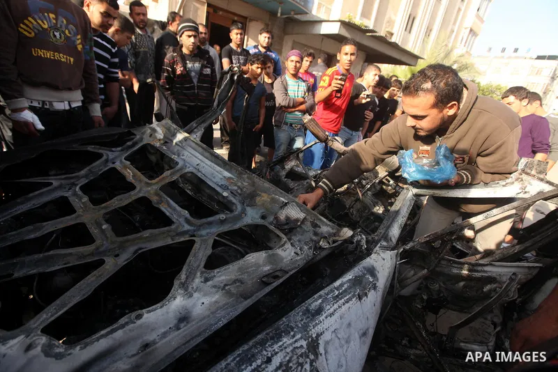 Palestinians gather around a destroyed car which targeted by Israeli airstrike in the northen Gaza city, 19 November, 2012. Israeli aircraft killed A Palestinian and wounded two others in the raid. Media reports that Isr...