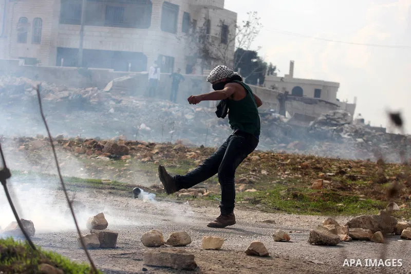 A Palestinian protester kicks a tear gas canister at Israeli soldiers during minor clashes against Israel's military operation in the Gaza Strip, in the West Bank village of Birzeit, near Ramallah November 19, 2012. Isra...