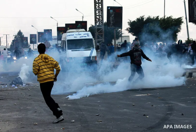 Palestinians run cover from tear gas during clashes against Israel's military operation in the Gaza Strip, in the West Bank city of Nablus on November 19, 2012. Israeli air strikes killed 22 Palestinians, hiking the Gaza...