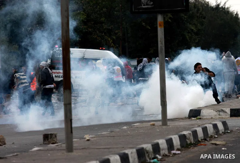 Palestinians take cover from tear gas during clashes against Israel's military operation in the Gaza Strip, in the West Bank city of Nablus on November 19, 2012. Israeli air strikes killed 22 Palestinians, hiking the Gaz...