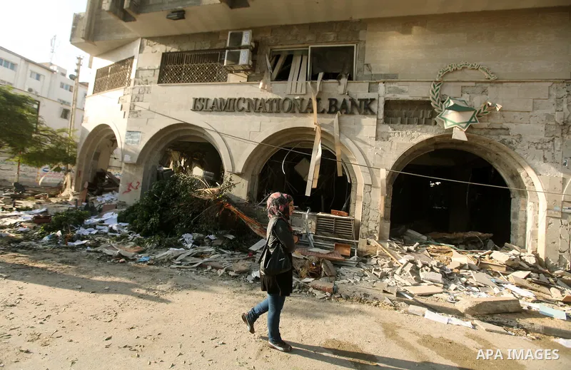 A Palestinian woman walks in front of the damage after an Israeli air strike on the Islamic National Bank building in Gaza City on November 20, 2012. Israeli leaders discussed an Egyptian plan for a truce with Gaza's rul...