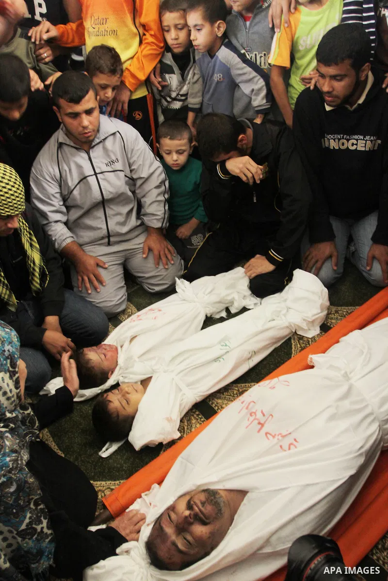 Palestinian mourners gather around the bodies of Foud Hijazi, 45, and his sons Suhaib, 2, and Mohammed, 4, killed in an Israeli strike, during their funeral at a mosque in the Jebaliya refugee camp, in Gaza Strip, Tuesda...