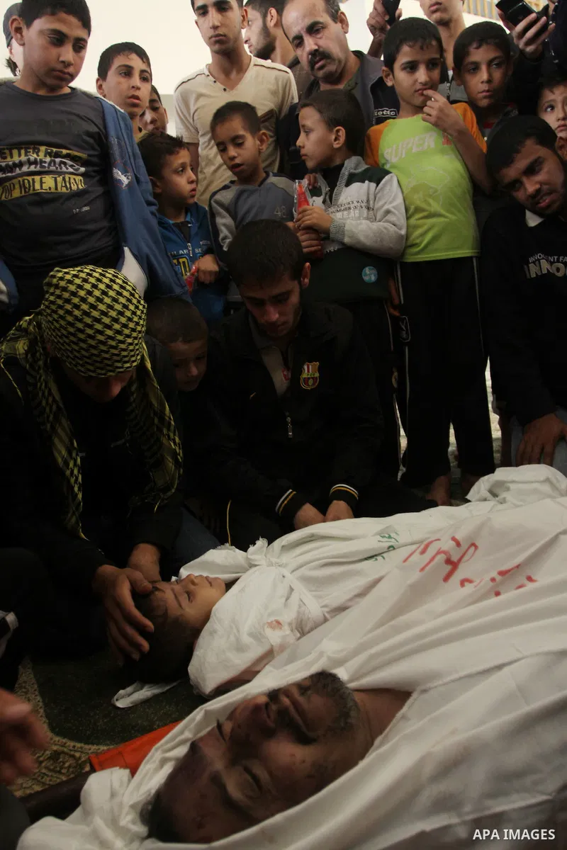 Palestinian mourners gather around the bodies of Foud Hijazi, 45, and his sons Suhaib, 2, and Mohammed, 4, killed in an Israeli strike, during their funeral at a mosque in the Jebaliya refugee camp, in Gaza Strip, Tuesda...