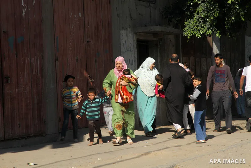 Palestinians get out of their houses after Israeli aircraft threatened to target the area, in the Jebaliya refugee camp, in Gaza Strip, Tuesday, Nov. 20, 2012. Palestinian families are fleeing their homes destroyed by ai...